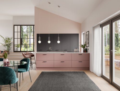 Kitchen with a pale pink island with black handles, dark grey cabinets are tall and behind the island.