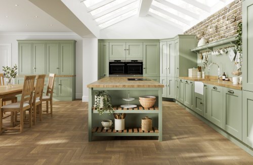 A pale green laura ashley whitby kitchen with wooden floor and wooden worktops shown with a kitchen island